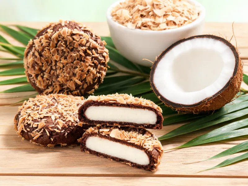 Runde Schoko-Kekse mit Kokosraspel-Hülle, einige halbiert mit weißem Kokos-Keksteig innen (KI-generiertes Bild)