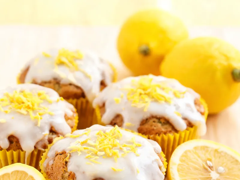 Zitronen-Muffins mit weißem Zitronenguss und Zitronenschale (KI-generiertes Bild)