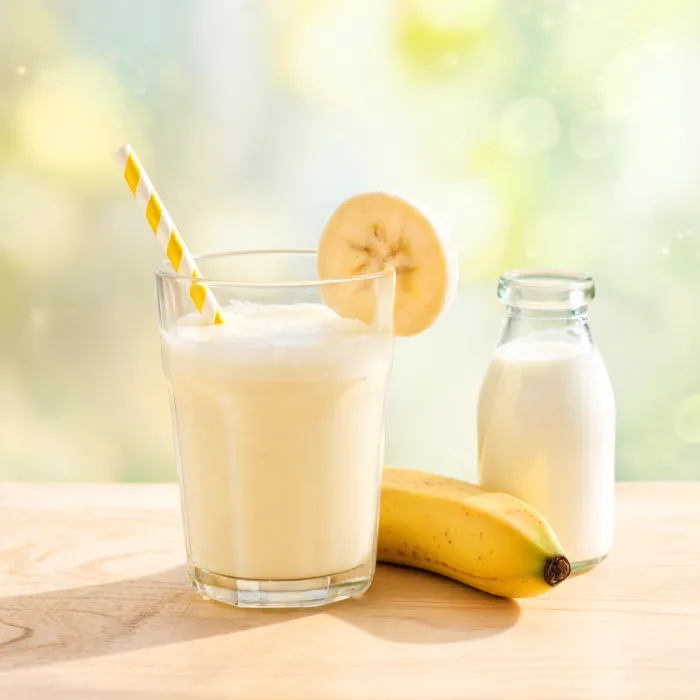 Glas selbstgemachte Bananenmilch mit Bananenscheibe am Rand (KI-generiertes Bild)