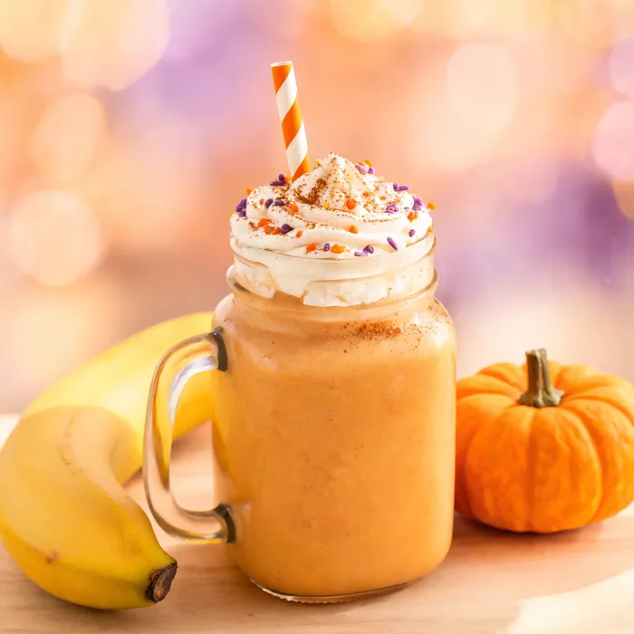 Oranger Kürbis-Bananen-Milchshake mit Sahnehaube und Zimt (KI-generiertes Bild)