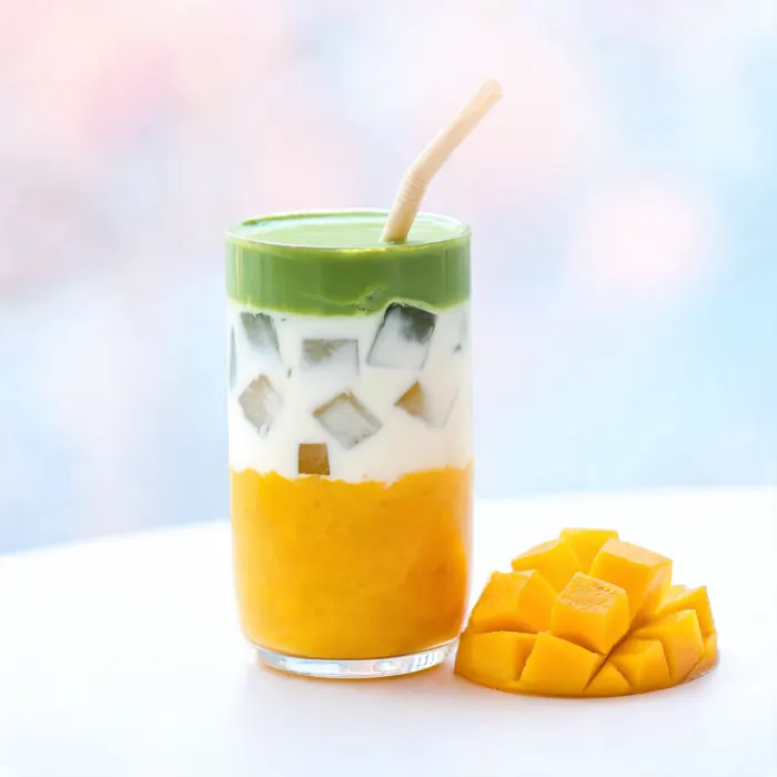 Geschichtetes Getränk mit Mango unten, Milch in der Mitte und grünem Matcha oben (KI-generiertes Bild)