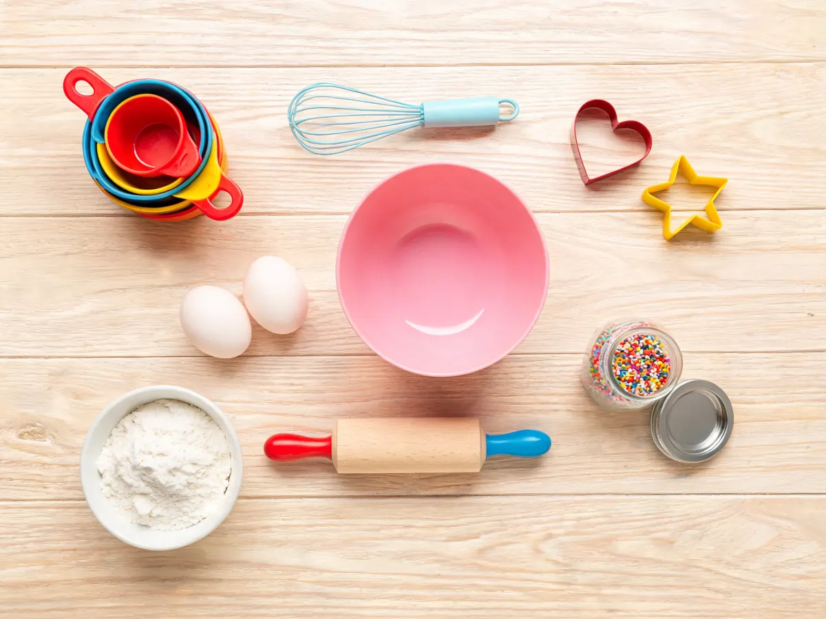 Bunte Backutensilien, Ausstechformen und Streusel auf einem Holztisch (KI-generiertes Bild)