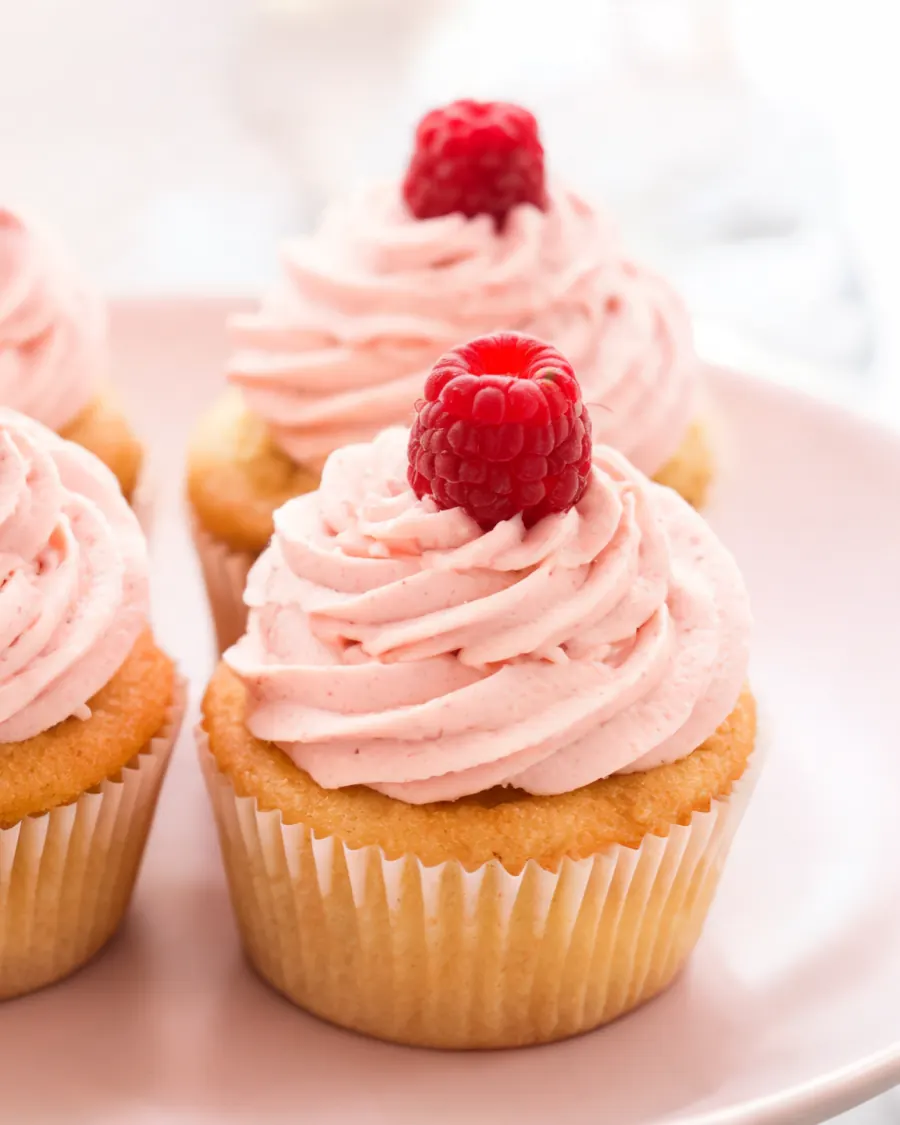 Vanille-Cupcakes mit rosa Himbeer-Frosting und Himbeeren (KI-generiertes Bild)