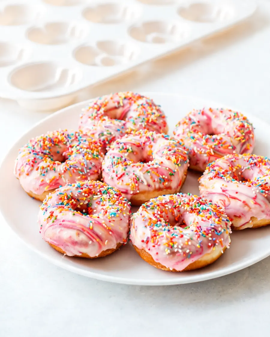 Gebackene Donuts mit rosa Glasur und bunten Streuseln (KI-generiertes Bild)