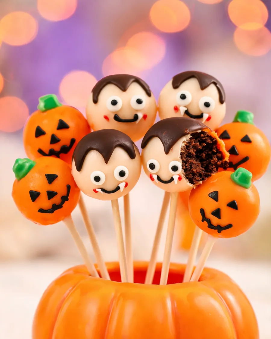 Schoko-Cake-Pops als Kürbisse und als Vampire mit kleinen Zähnen (KI-generiertes Bild)