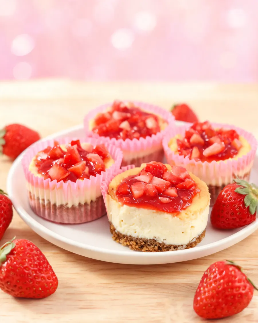 Käsekuchen-Muffins mit Keksboden und Erdbeer-Topping in rosa Papierförmchen (KI-generiertes Bild)